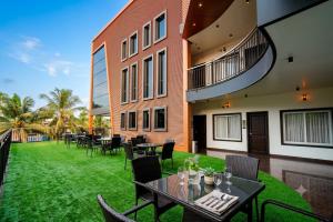 eine Terrasse mit Tischen und Stühlen und ein grüner Rasen in der Unterkunft Time Square Inn in Erāttupetta
