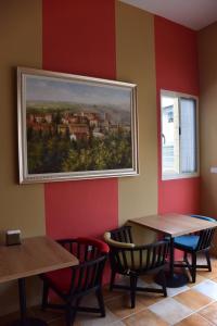 a painting hanging on a wall with two tables and chairs at Red Roof B&B in Taitung City