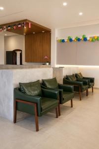a row of green chairs in a waiting room at Hotel Mazzuco in Araranguá