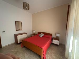a bedroom with a bed with a red bedspread and a mirror at La casa di GiòGiò in San Vito lo Capo
