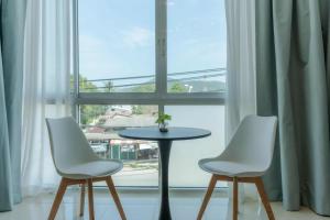 two white chairs and a table in front of a window at PGD brown city view in Rawai Beach