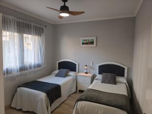 a bedroom with two beds and a ceiling fan at Apartamentos Mareventus in Sanxenxo