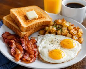 a plate of breakfast food with eggs bacon and toast at Hotel The Sun B&B in New Delhi