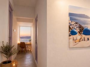 a room with a view of the ocean and a painting on the wall at Mamma Mia Santorini Suites-Volcano -Caldera -Sunset View in Fira