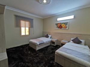 a hotel room with two beds and a window at بيوت عطلات البيت الريفي للضيافه السياحي in Al Namas