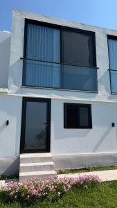 a white building with black windows and some pink flowers at Escape Suites in Dhërmi