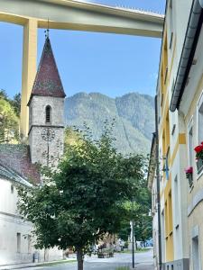 a building with a clock tower and a tree on a street at Mountain Nest Apartment in Schottwien