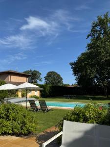 a pool with two lounge chairs and an umbrella at ViLLA HELENA - anciennement LE CLOS D'IGNAC in Lège-Cap-Ferret