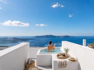 a man sitting in a bath tub on a balcony at Mamma Mia Santorini Suites-Volcano -Caldera -Sunset View in Fira