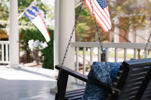 a bench with an american flag and a pillow on it at The Edenton Collection – Captain’s Quarters Inn in Edenton