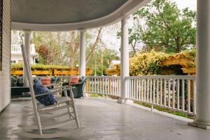 a rocking chair on a porch with a fence at The Edenton Collection – Captain’s Quarters Inn in Edenton +44 photos