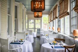 a restaurant with white tables and chairs and windows at The Edenton Collection – Captain’s Quarters Inn in Edenton
