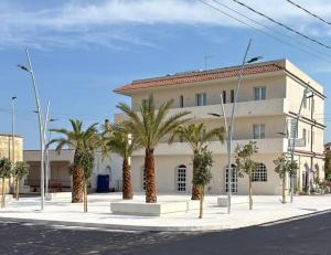 a building with palm trees in front of a street at Hotel Noto Marina Meeting Vista Mare in Noto Marina +15 photos