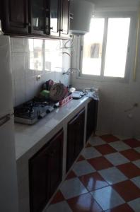 a kitchen with a stove and a checkered floor at Resicence jaouharat zarkaa in M'diq