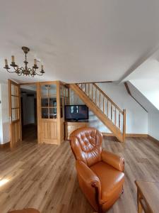 a living room with a leather chair and a staircase at Penzion Manský Dvůr in Dolní Žandov