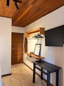 a room with a table and a television on a wall at Pituba Vile - Apartamento Jardim in Itacaré