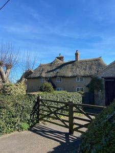 a large house with a fence and a thatch roof at The Rest-Well Lodge in Sherborne