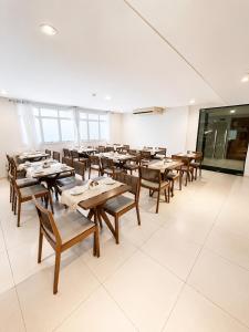 a dining room with wooden tables and chairs at Atlântico Golden Apart Hotel in Santos