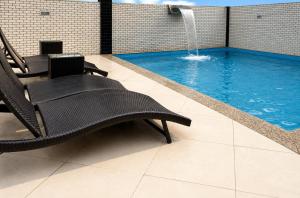 a swimming pool with a chair and a fountain at Atlântico Golden Apart Hotel in Santos