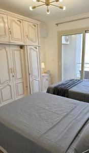 a bedroom with two beds and cabinets and a window at Stylish Flat at Jannah Compound Sheikh Zayed in Sheikh Zayed