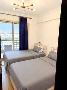two beds in a room with a window at Stylish Flat at Jannah Compound Sheikh Zayed in Sheikh Zayed