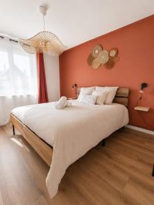a bedroom with a large bed with orange walls at La petite maison secrète in Abbeville