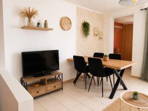 a living room with a dining room table and a television at La petite maison secrète in Abbeville