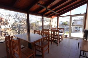 a dining room with tables and chairs and windows at El Retorno Hostel in Puerto Madryn