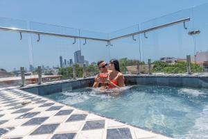 a man and a woman sitting in a swimming pool at Hotel Monaguillo de Getsemaní in Cartagena de Indias