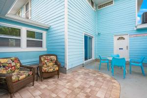 a patio with two chairs and a table on a blue house at Everglades Villa - Sleeps 8 - Walk to Siesta Beach in Siesta Key