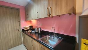 a kitchen with a sink and a pink wall at 1556 Shore Residences tower C - MOA in Sampong