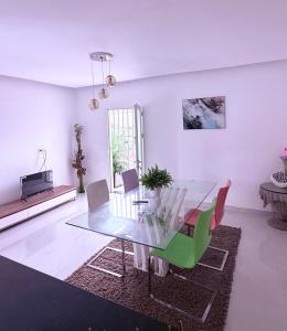 a dining room with a glass table and colorful chairs at Residencial Ru-B in Luanda