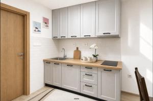 a kitchen with white cabinets and a sink at Apartmani Resimic in Ivanjica