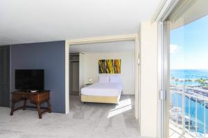 a bedroom with a bed and a television and a balcony at Ilikai Marina 1386 in Honolulu