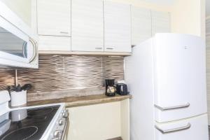 a kitchen with white cabinets and a sink and a refrigerator at Ilikai Marina 1386 in Honolulu +20 photos