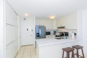 a white kitchen with a counter and two stools at Ilikai Marina 1688 in Honolulu +23 photos