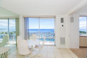 a dining room with a white table and chairs and windows at Ilikai Marina 1688 in Honolulu