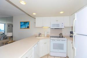 a kitchen with white cabinets and a white refrigerator at Ilikai Marina 382 in Honolulu +25 photos