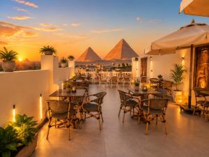a patio with tables and chairs with pyramids in the background at Hadayek Al-Ahram Guest House - حدائق الاهرام جيست هاوس in Giza
