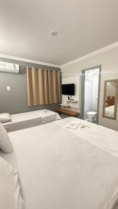 a bedroom with two large white beds and a television at Nobrezafiori Diroma FIORI taxas de Roupas de Cama Banho e taxas do hotel valor a pagar na recepcao do hotel OBS MENOR DE 18 anos desacompanhado dos pais tem que ter autorizacao com RECONHECIMENTO de firma no cartório in Caldas Novas +65 photos