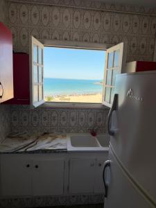 a kitchen with a window with a view of the beach at Complexe la brise tour 8 appt 815 in La Goulette