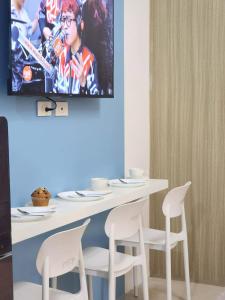 a dining room table with white chairs and a tv on the wall at 438 Shore Residences tower B - MOA in Sampong