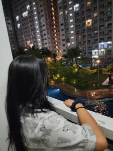a woman looking out of a window at a city at 438 Shore Residences tower B - MOA in Sampong