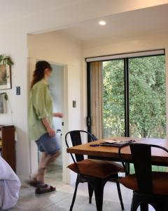 a woman walking through a room with a table and chairs at Slow Stay at Roebuck Farm in New Plymouth +16 photos
