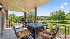 a porch with a table and chairs and a grill at TeeTime Green On the Fairway in Camdenton