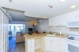 a kitchen with white cabinets and a living room at Ilikai Tower 1403 in Honolulu