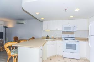 a kitchen with white cabinets and white appliances at Ilikai Tower 1403 in Honolulu