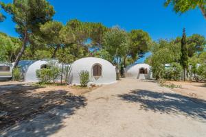 a group of white domes with trees in the background at Camping Villaggio Egad in Favignana
