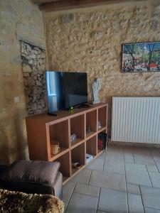 a living room with a television on a wooden entertainment center at Les Rochers de Bayac in Bayac