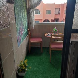 a room with a table and two chairs with green carpet at lux appartement avec piscine in El Jadida